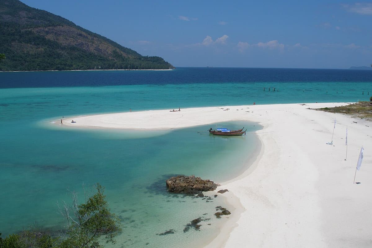 A white sandbar and a longtail boat in turquoise water at Koh Lipe