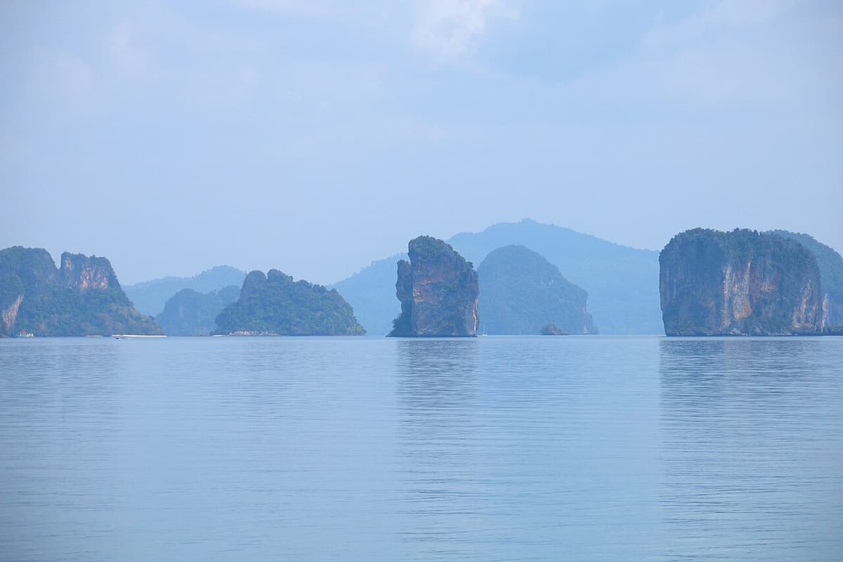 Limestone islands of Phang Nga Bay seen across calm water from Koh Yao Noi