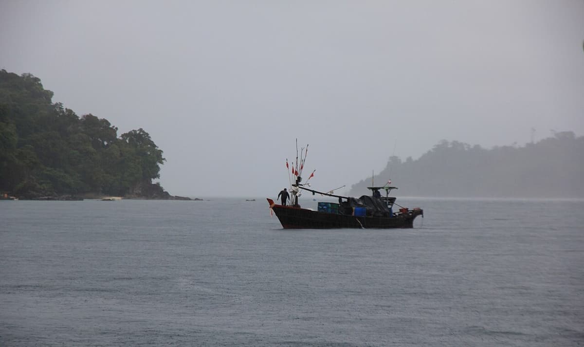 A wooden fishing boat between forested islands in the Mergui Archipelago