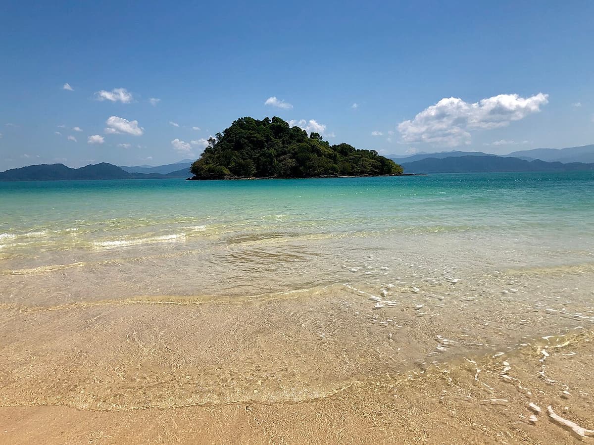 A small wooded islet off a shallow sandy beach on Koh Phayam